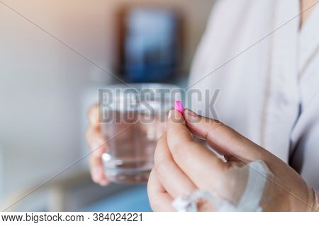 Patient Eating Medication To Treat Disease, Holding Pill Tablet And Glass Of Water In Hands For Taki