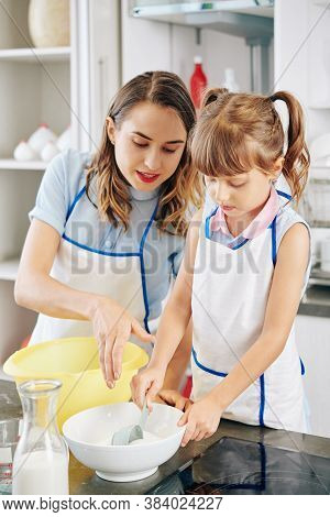 Mother Telling Daugter How Much Sugar To Add In Bowl When Thay Are Making Cake Dough
