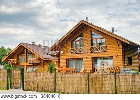 Modern Wooden House With Big Windows Surrounded By Bamboo Fence In The Suburb. Building Of Houses Fo
