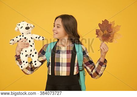 Nourish Child With Game. Small Child Hold Toy Doll And Autumn Leaves. Little Girl Play Game In Schoo