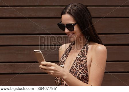 Happy Smiling Woman Traveler Using Mobile Smart Phone, Wearing Bikini Clothing Standing Over Black W