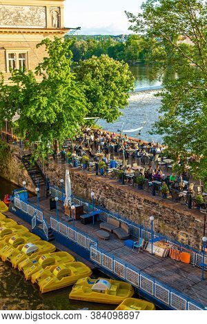 Klub Lavka Restaurant In Prague. People Are Resting On A Summer Terrace Overlooking The Vltava River