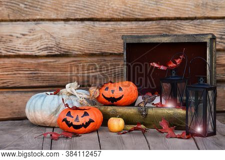 Pumpkins, Lanterns With Light, Vintage Chest On A Wooden Table
 