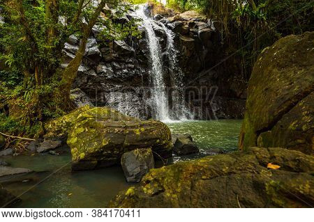 Tropical Landscape. Beautiful Hidden Waterfall In Rainforest. Foreground With Big Stones. Adventure 