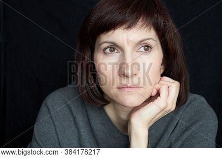 Mature, Middle-aged Woman Looks Anxiously Ahead, Chin Propped On Hand. Close-up Portrait.