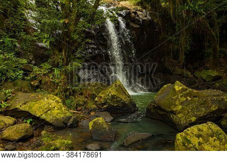 Tropical Landscape. Beautiful Hidden Waterfall In Rainforest. Foreground With Big Stones. Adventure 