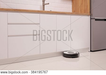 Robot vacuum cleaner on a tiled kitchen floor