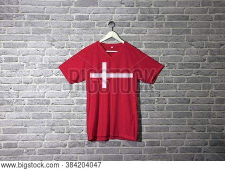 Denmark Flag On Red Shirt And Hanging On The Wall With Brick Pattern Wallpaper, A White Scandinavian
