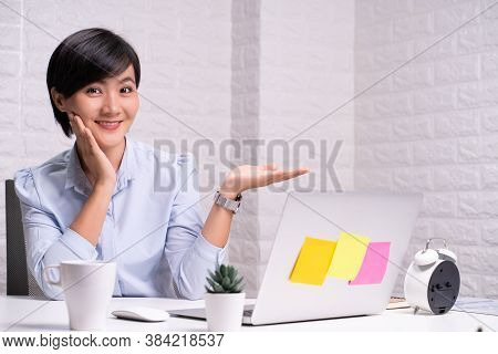 Happy Woman Sitting At Home Office And Pointing To Copy Space