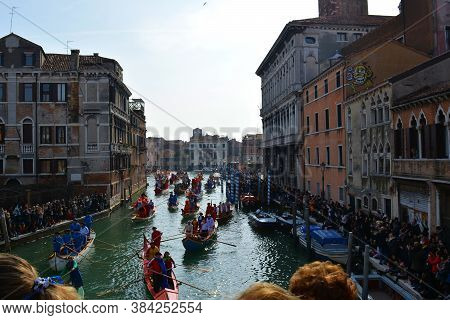 Venice, Italy 02 12 2017: Gondolas On Venetian Canal During Carnival Regata Parade Full Of Tourists
