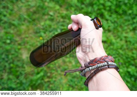 A Hand Of A Hippie, Hipster Holding A Bottle Of Alcohol, Beer. Young People With Alcohol Addiction C