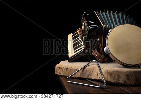 Old Accordion, Tambourine And Triangle On Rustic Wooden Surface With Black Background And Low Key Li