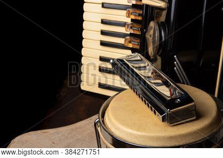 Old Accordion, Harmonica And Bong On Rustic Wooden Surface With Black Background And Low Key Lightin