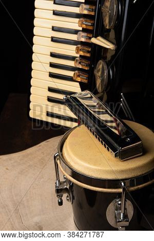Old Accordion, Harmonica And Bong On Rustic Wooden Surface With Black Background And Low Key Lightin