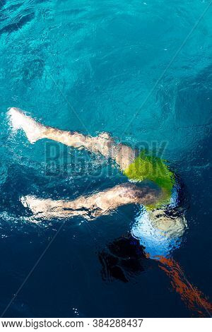 Boy Diving Underwater In An Arc In Swimming Pool