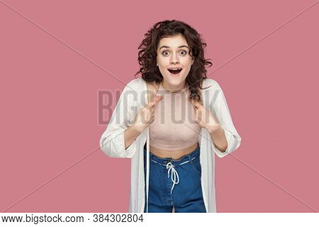 Me? Portrait Of Surprised Beautiful Brunette Young Girl With Curly Hairstyle In Casual Style Pointin