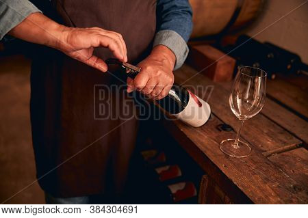 Winemaker In Apron Opening Bottle Of Wine