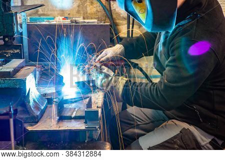 Electric Welding Process. Worker In Welding Mask. Yellow Sparks Fly To The Sides. Bright White.