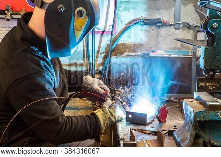 Electric Welding Process. Worker In Welding Mask. Yellow Sparks Fly To The Sides. Bright White.