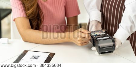 Panoramic Close up Asian woman customer make contactless credit card payment after eating out in new normal social distance restaurant to reduce touching. Online contactless and technology concept.