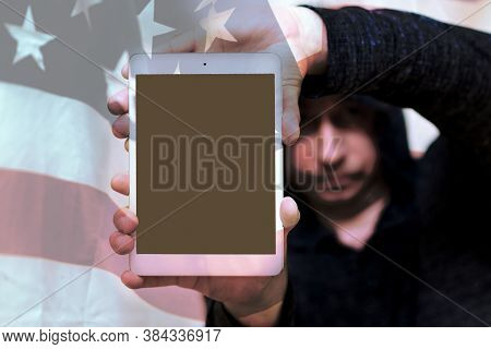 A Blurry Man In Gray Sweatshirt Hood Holds Tablet Pc Computer With Blank Screen For Copy Space. Usa 
