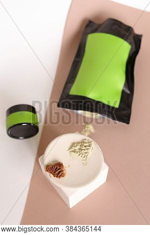 Focus On White Plate With Clay Powder Near Doypack And Jar With Cosmetic Products And Green Space Fo