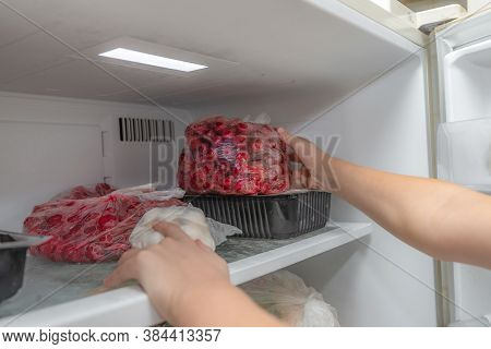 A Woman Puts Frozen Fruit Products In The Freezer, For Long-term Preservation.