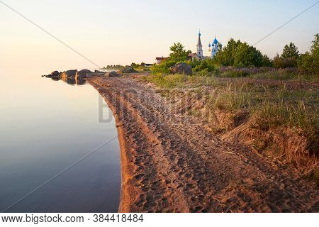 The Shore Of Lake Peipus At Sunset. Church Of The Apostles Peter And Paul In Vetvenik, Pskov Region.