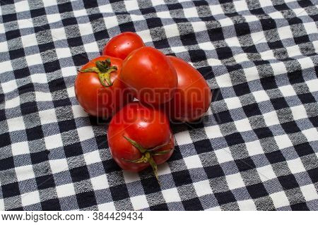 juicy red tomatoes in table cloth . caro background