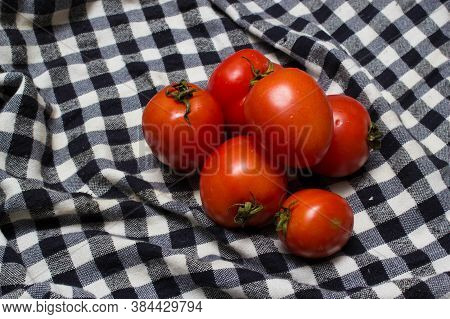 juicy red tomatoes in table cloth . caro background