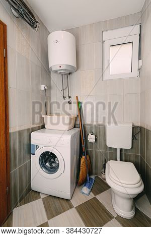 Toilet, Washing Machine, Boiler, Bowl, Broom And Mop In The Bathroom.