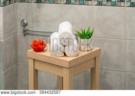 Light Tile With Pattern. Spa Composition Of White Rolled Towels On The Wooden Stool. Green Flower. R