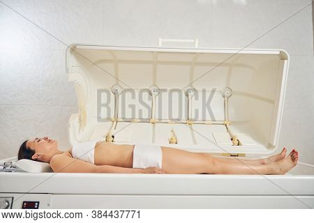 Young Woman In Beauty Center Undergoing Body Wrap Procedure