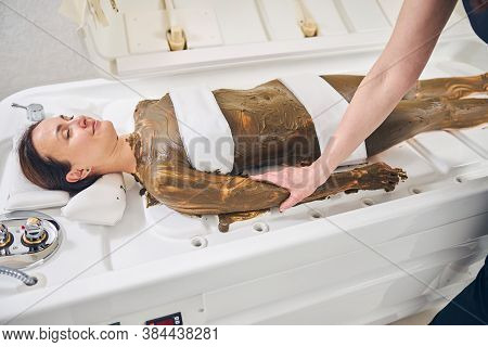 Hand Of Cosmetologist On The Arm Of Her Relaxed Client