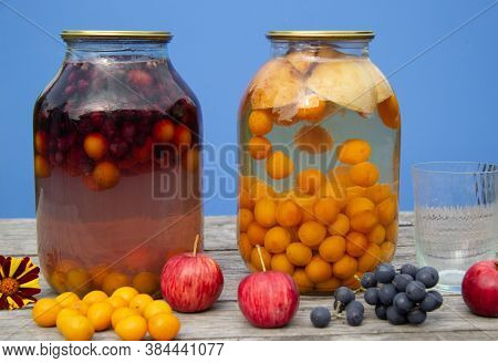 Two-litre Cans With Compote Stand On A Wooden Surface. There's A Blue Wall In The Back. Homemade Har