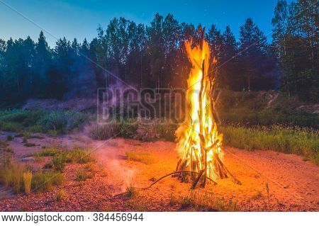 Landscape Of Forest At White Night. Close-up Of Huge Fire. Traditional Midsummer Ligo Celebration.
