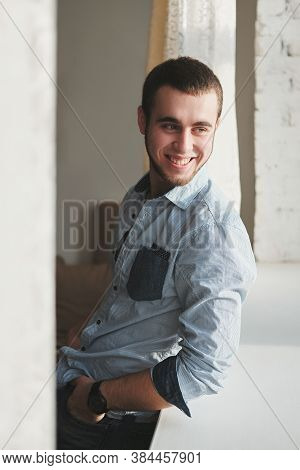 Handsome Man Wearing A Black Jacket And Jeans Sitting Down Intside