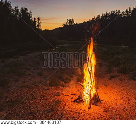 Midsummer Ligo Celebration. Top View Of Huge Fire On The River Shore In The Forest. Scenic Landscape