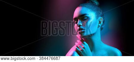 High Fashion model woman in colorful bright sparkles posing in studio in neon lights? 