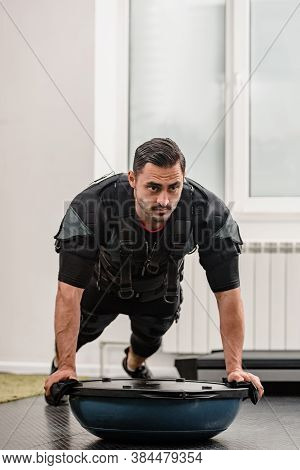 Strong Male Athlete In Ems Costume Doing Plank Exercise On Bosu Ball