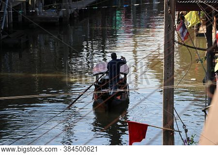 Life Along The Canal And Boatman Rowing The Thai Traditional Small Rowboat On The Canal At Damnoensa