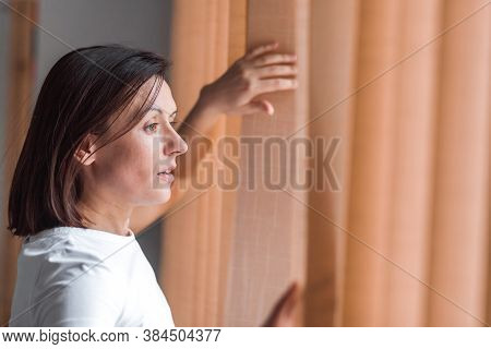 Photo Of Side View Of Pretty Woman Touching Curtains And Looking Straingt.