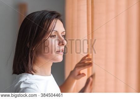Photo Of Side View Of Pretty Woman Touching Curtains And Looking Straingt.