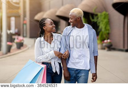 Limited Edition And Mega Discounts. Cheerful African American Couple With Shopping Bags Talking And 