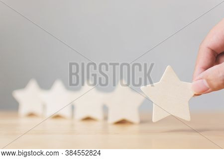 Hand Putting Wooden Five Star Shape On Wood Table. The Best Excellent Business Services Rating Custo