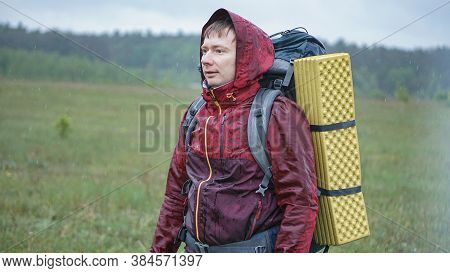 Hiker With A Large Backpack Getting Wet In The Rain While Traveling In The Mountains