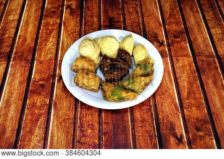 Oriental, Turkish, Azerbaijani Baklava Sweets In A White Plate On A Brown Wooden Table.