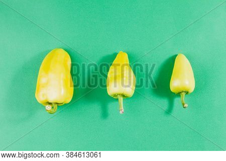 Three Green Ripe Peppers Lie In Ascending Order From Small To Large On A Pastel Green Background Wit