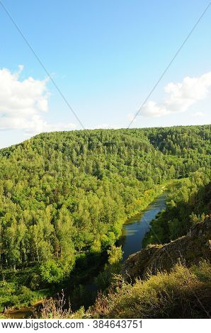 A Fragment Of A River Curving Flowing Through A Dense Coniferous Forest.