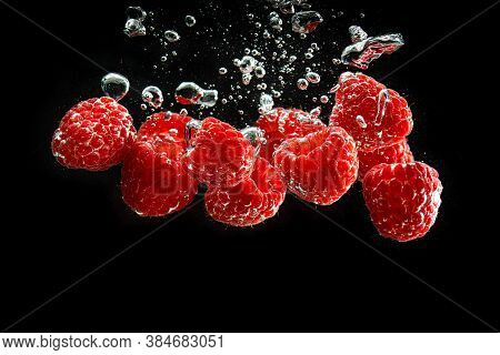 Raspberries Splashing Into Clear Water Isolated On Black Background. Healthy Fruits Concept. Copy Sp